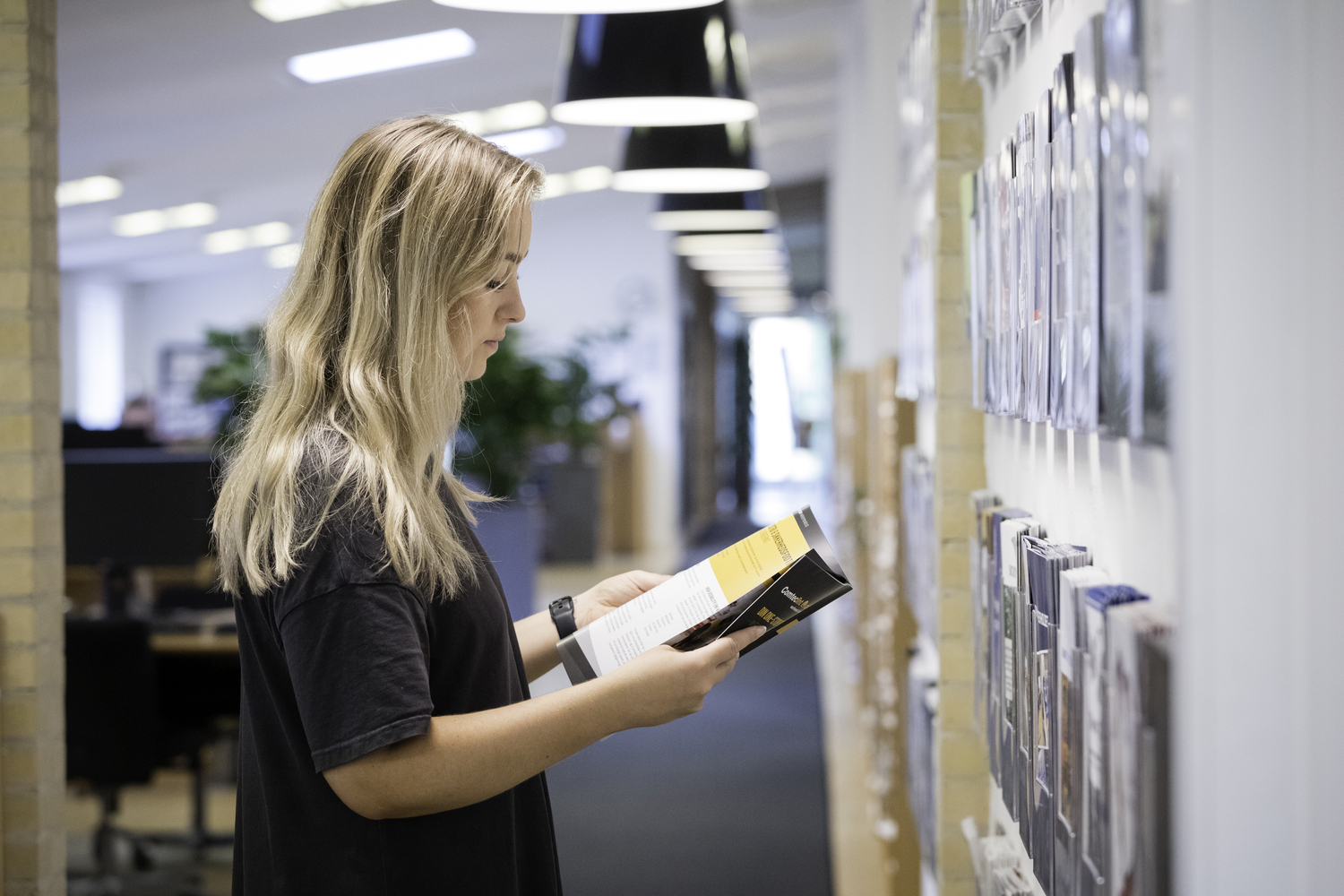 Blond woman looking at brochure at brochure wall in JS office